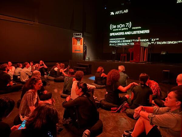 A group of people sat listening in semi-darkness
