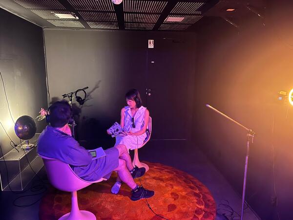 Two people listening in a softly lit black room