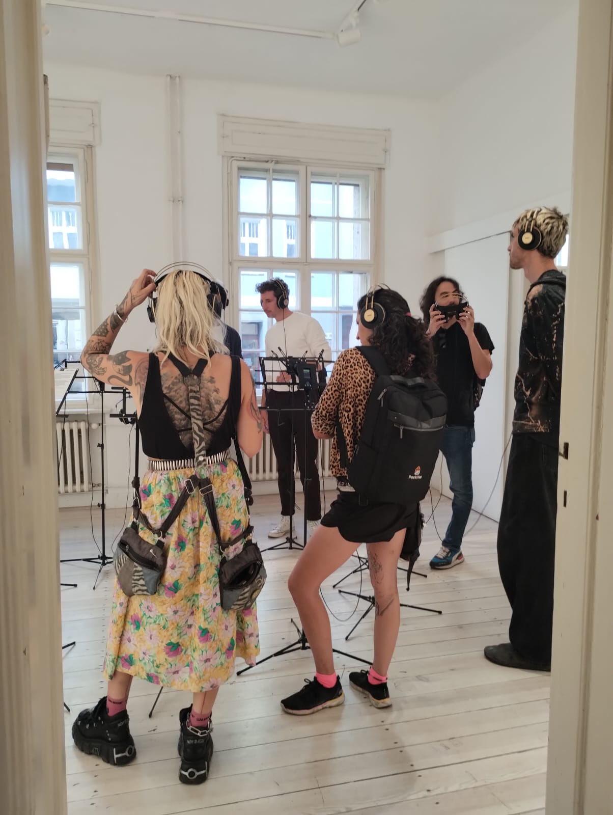 A photo from the opening of a group of people listening to Miranda July's series.